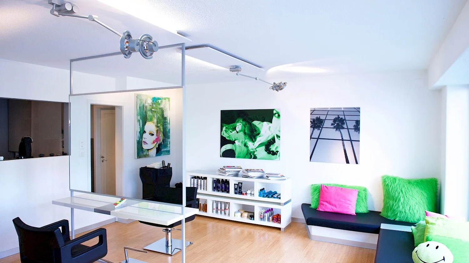 A bright open salon space with vibrant green artwork, a waiting bench with colorful cushions, and product shelves.