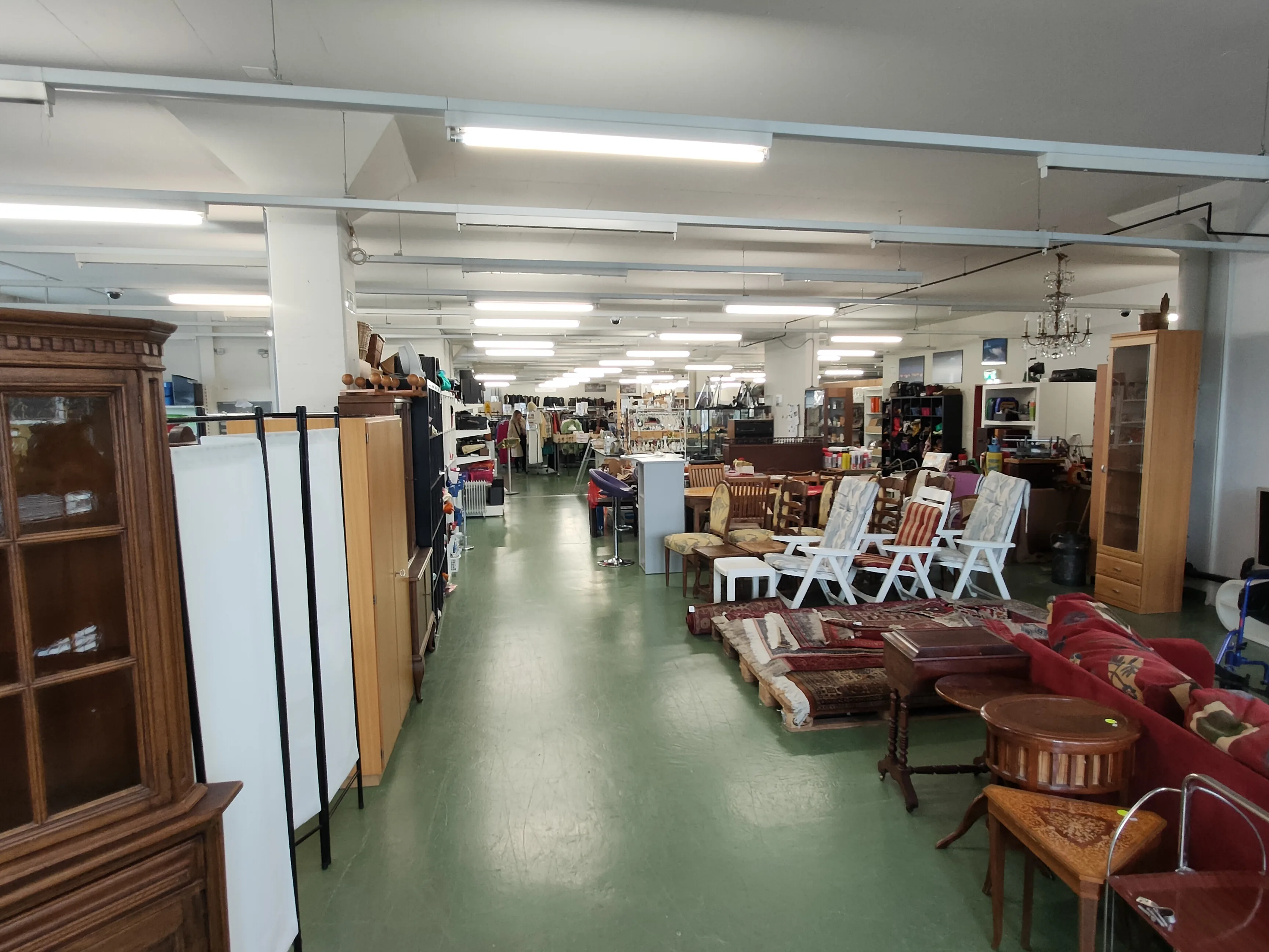 A spacious secondhand store floor packed with furniture, chairs, and household goods.